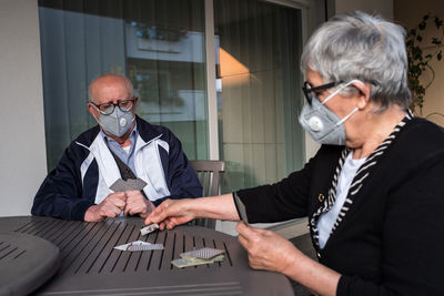 Italian's older people lockdown. a married couple play with game of the cards. 