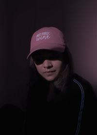 Portrait of a young woman against black background