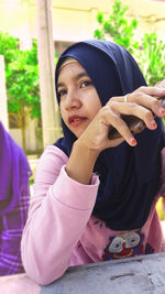 Woman in hijab sitting at table outdoors