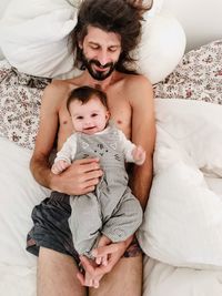 High angle view of father and daughter on bed