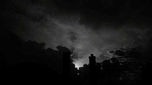 Low angle view of silhouette factory against sky at night