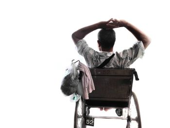 Rear view of man sitting on seat against white background