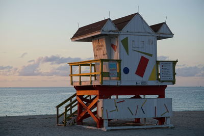 Lifeguard hut on beach against sky during sunset