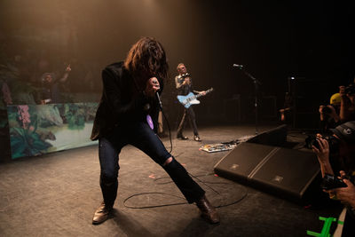 Full length of friends playing at music concert