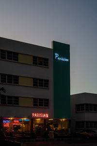 Low angle view of illuminated sign against sky at night