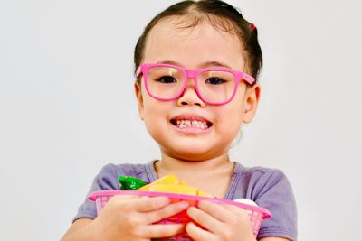 Portrait of boy holding ice cream against white background