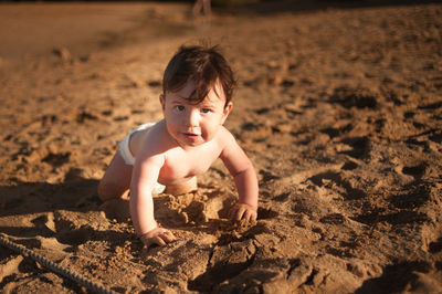 Portrait of shirtless boy on sand