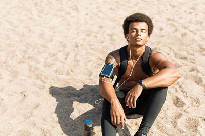 Young man with eyes closed sitting at beach