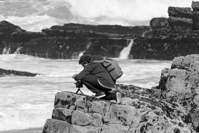 Rear view of man on rock at shore