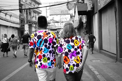 Rear view of people walking on street in city