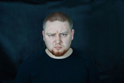 Close-up portrait of serious man against black backdrop