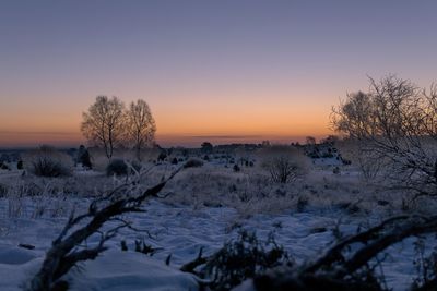 Scenic view of snow covered landscape against sky at sunset