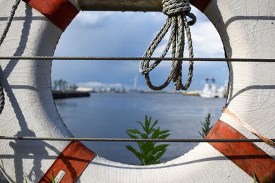 Close-up of rope hanging over sea against sky surrounded by a life ring