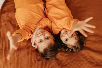 Children brother and sister hugging lying on the bed in the cozy interior of the bedroom of house