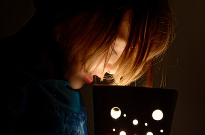 Portrait of little blonde girl in dim light looking towards a lamp