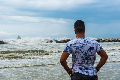 Rear view of man looking at sea against sky