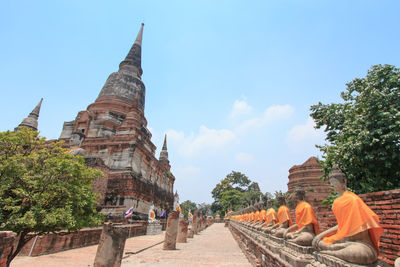 Buddha statues in row against sky at wat yai chai mongkhon