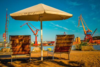 Chairs on beach against blue sky