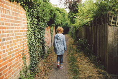 Rear view of young woman walking on footpath