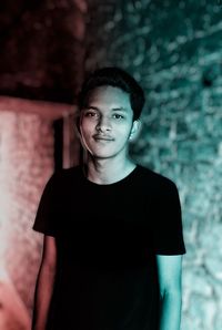 Portrait of young man standing against wall