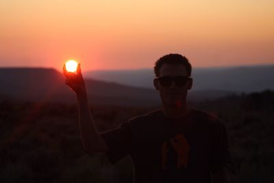 Optical illusion of silhouette man holding son at sunset