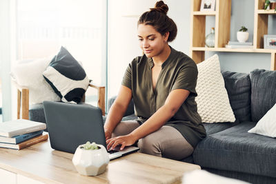 Young woman using mobile phone while sitting on sofa