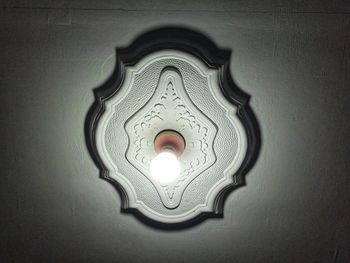 Low angle view of illuminated lamp on wall