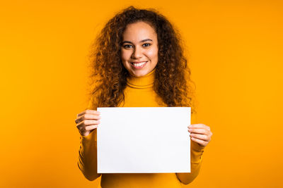 Portrait of a smiling young woman against yellow background