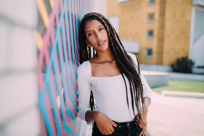 Portrait of smiling young woman leaning on wall