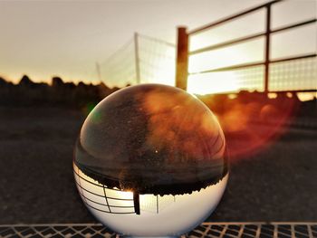 Close-up of crystal ball on railing against sky