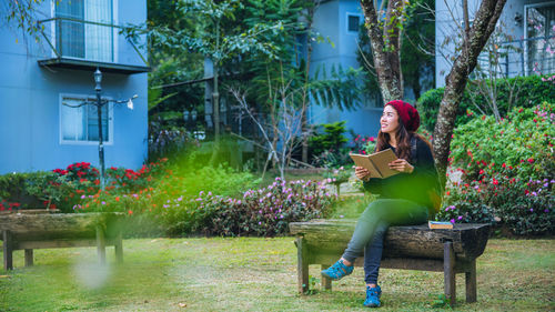 Full length of woman sitting on bench in park