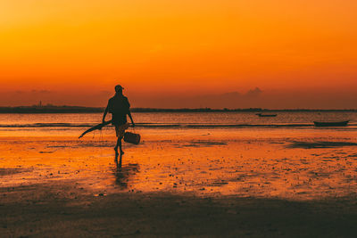 Silhouette woman walking at beach against sky during sunset