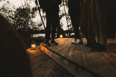 Low section of male and female friends standing over wooden steps during social gathering