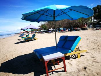 Chairs on beach against blue sky