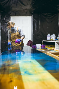 Female resin artist pouring resin tint onto artwork