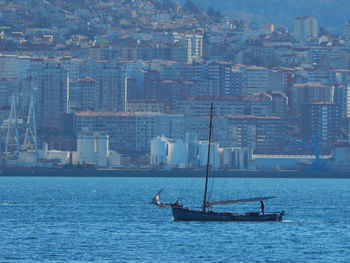 Sailboats sailing on sea by buildings in city