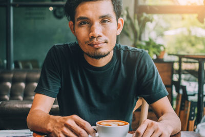 Portrait of man with coffee sitting in cafe