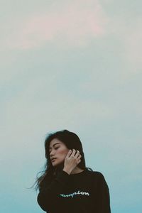 Young woman standing against sky