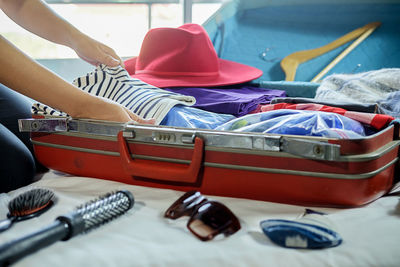 Cropped image of woman packing luggage on bed