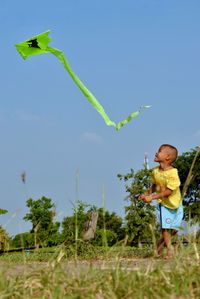 Full length of girl flying over field against clear blue sky