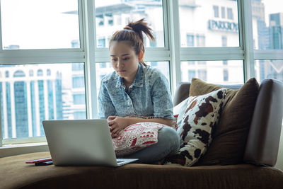 Young woman using mobile phone while sitting in office