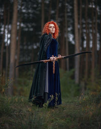 Portrait of woman standing on field in forest