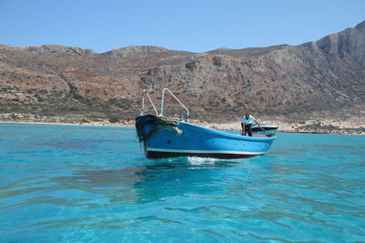 Boat in sea against clear blue sky