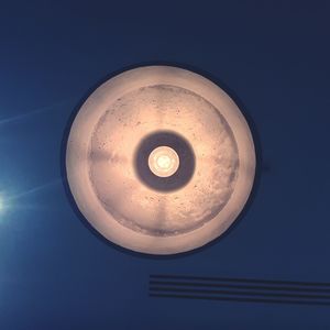 Directly below shot of illuminated pendant light against blue sky