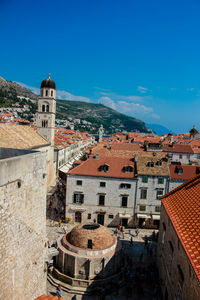 High angle view of buildings in town against blue sky