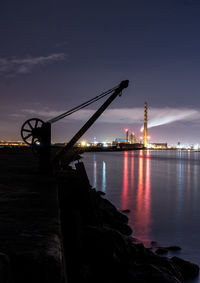 Illuminated pier over sea against sky at dusk