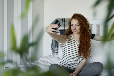 Portrait of young woman using phone while sitting outdoors