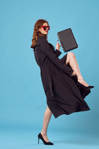 Woman holding umbrella against blue background