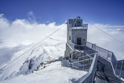 Built structure on snowcapped mountain against sky