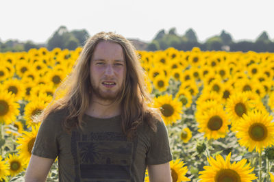 Portrait of young woman with yellow flowers in field